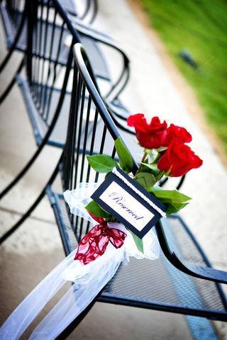 A row of chairs with red roses and a name tag that says reserved