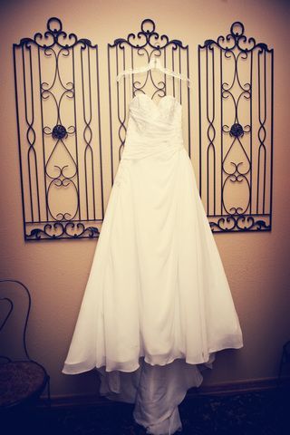 A wedding dress is hanging on a hanger on a wall.