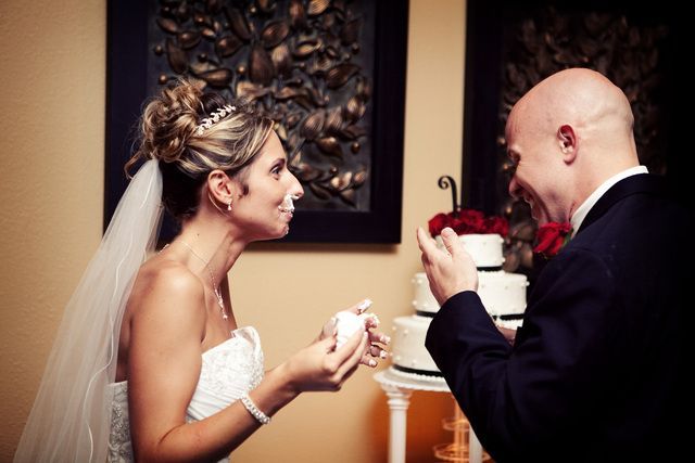 A bride and groom are cutting their wedding cake together