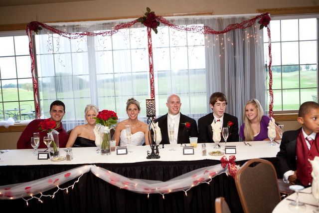 A group of people are sitting at a long table at a wedding reception.