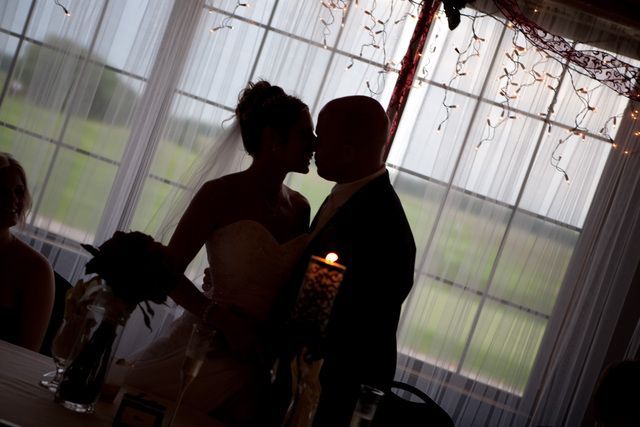 A bride and groom kissing in front of a window