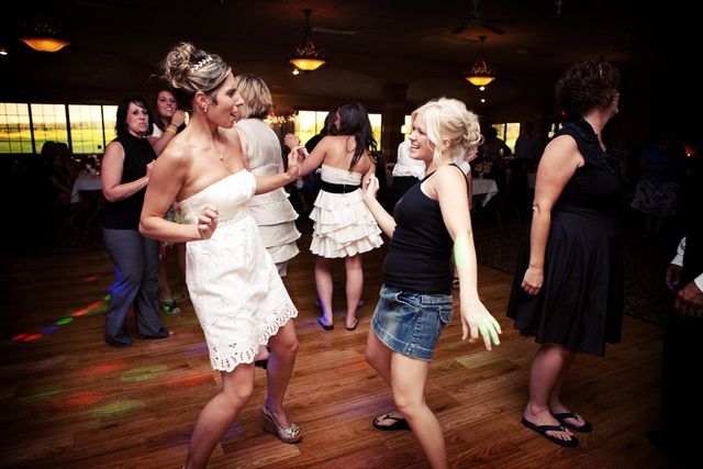 A group of women are dancing on a dance floor at a wedding reception.