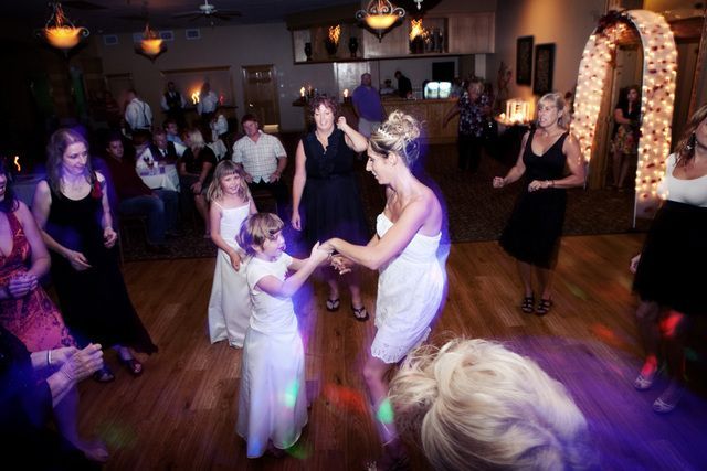 A group of people are dancing on a dance floor at a wedding reception.