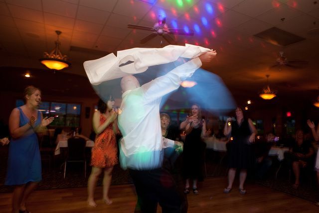 A group of people are dancing in a room at a wedding reception.