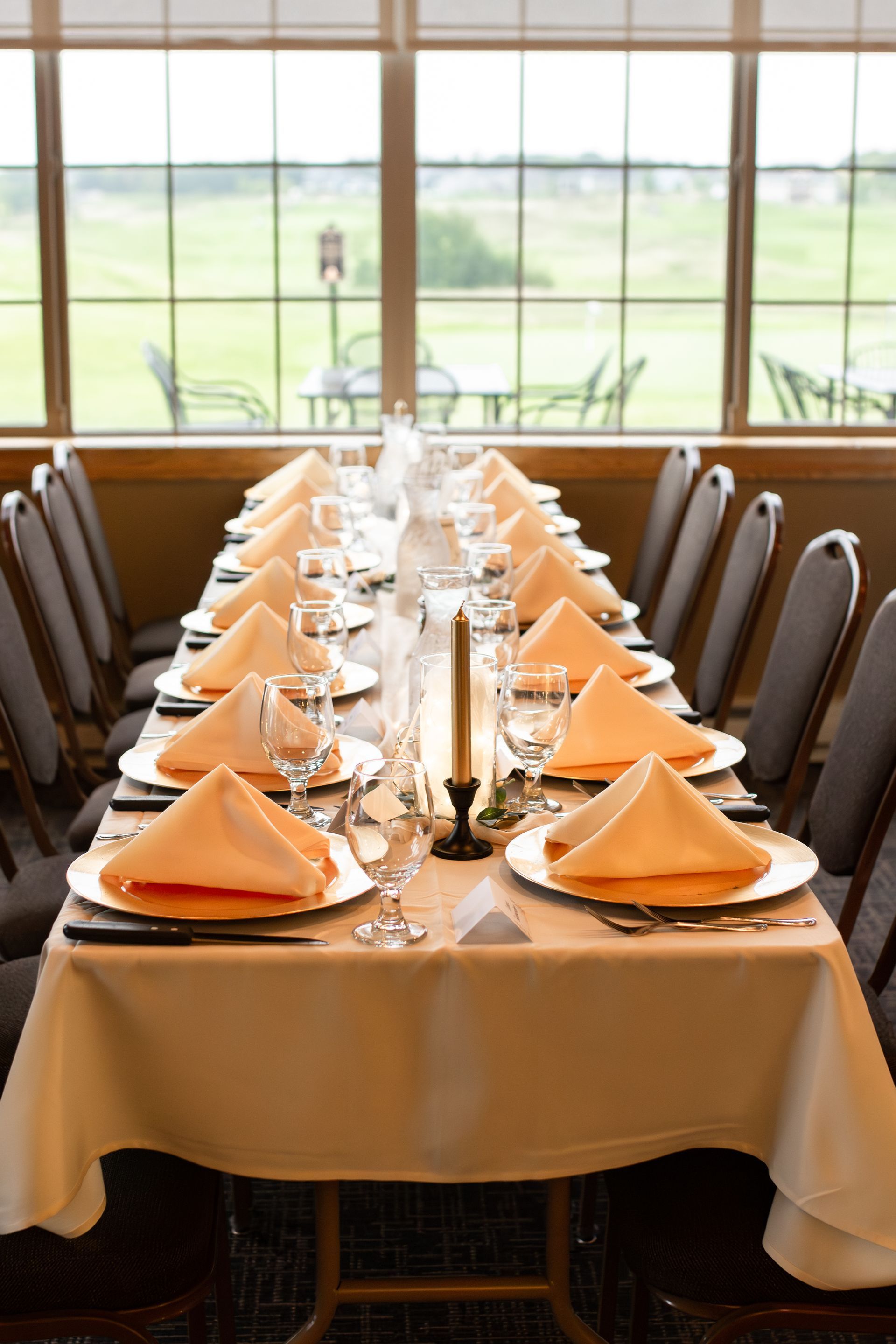 A long table with plates , napkins , candles and glasses set for a dinner party.