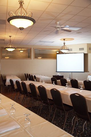 A conference room with tables and chairs and a projector screen.