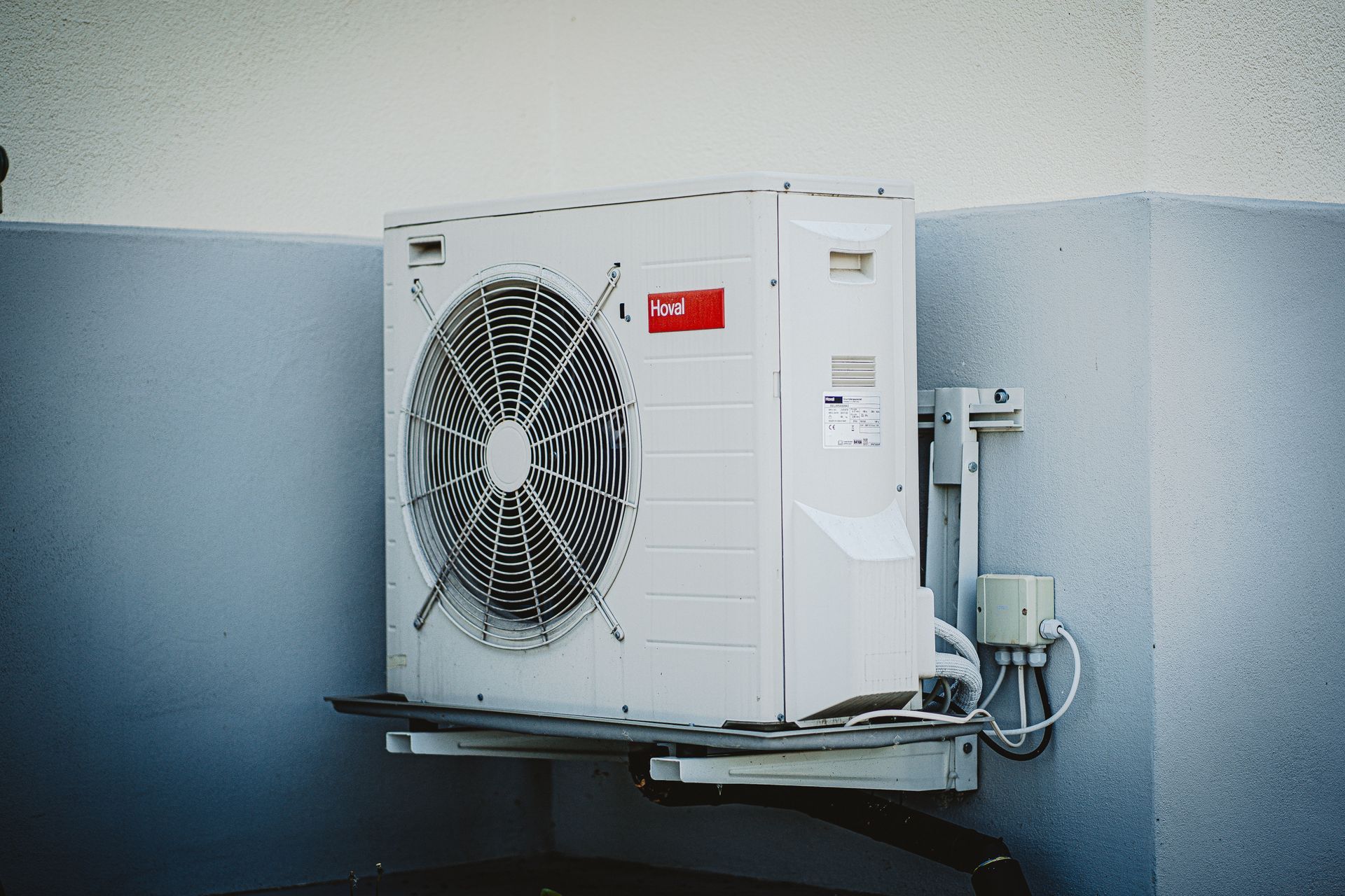 An air conditioner condenser unit mounted on an exterior wall.