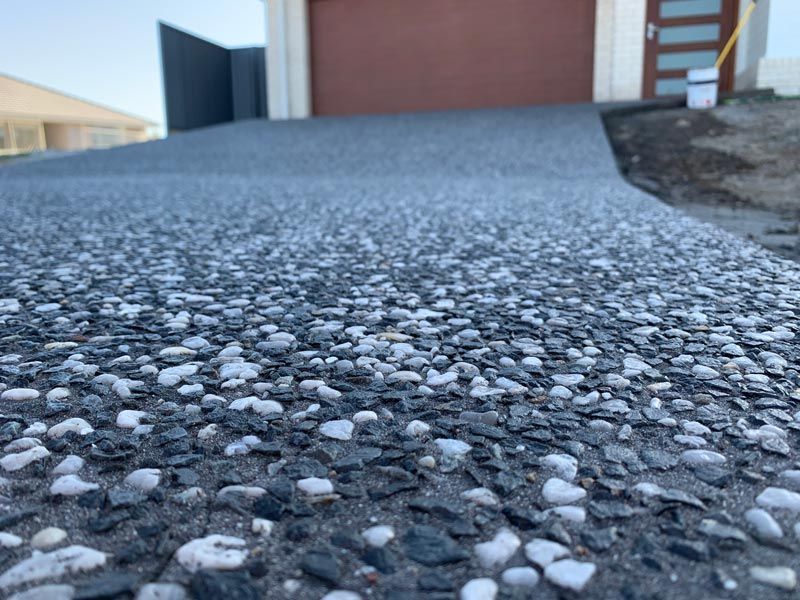 Close Up Pebble Driveway Red Garage Door — Brodie Wynter Concreting in Port Macquarie, NSW