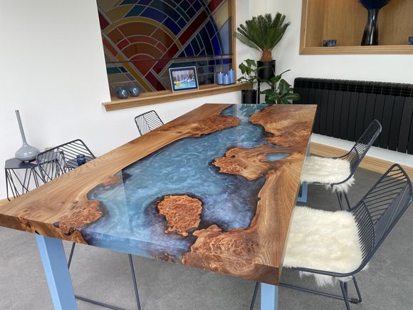 An elm river table with large burrs and light blue textured resin.