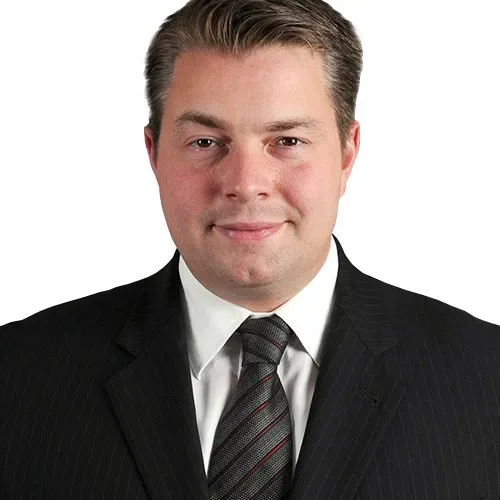 A man in a suit and tie is smiling for the camera