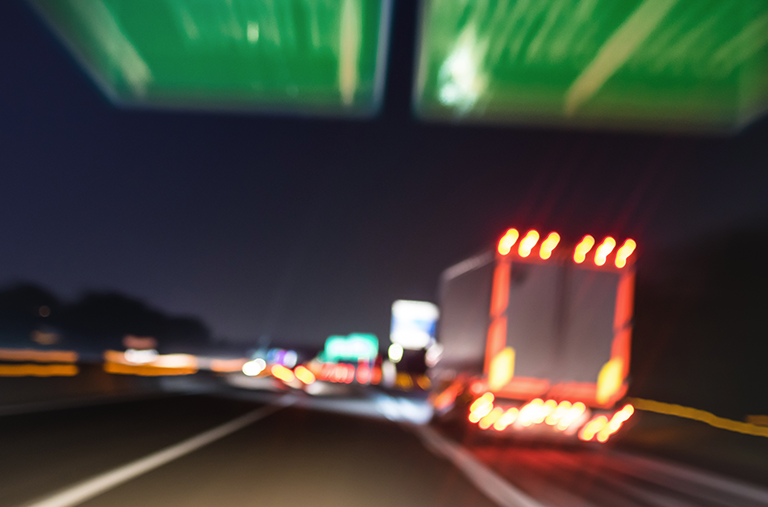 A blurry picture of a truck driving down a highway at night.