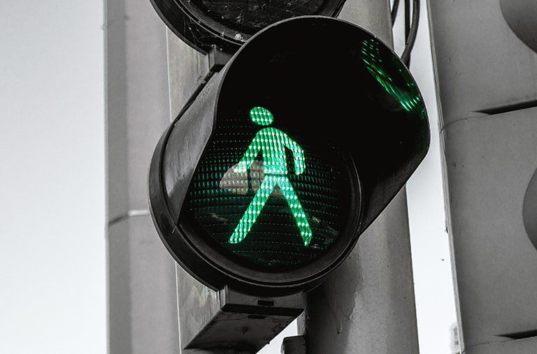 A green traffic light with a person walking on it
