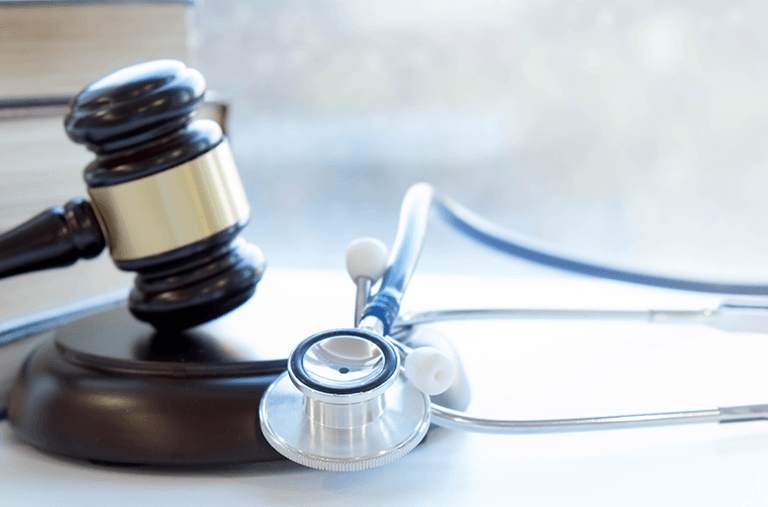 A stethoscope is sitting next to a judge 's gavel on a table.