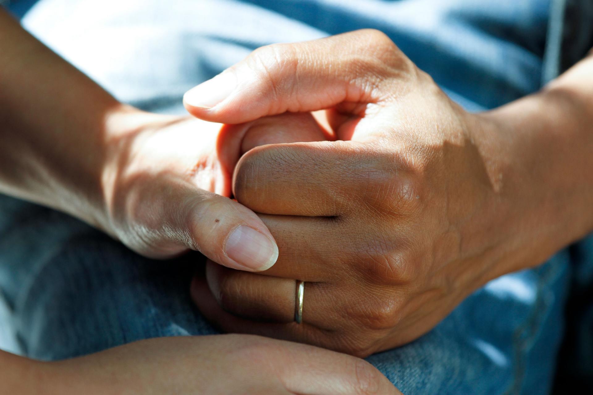 A woman is holding a man 's hand with a ring on her finger.