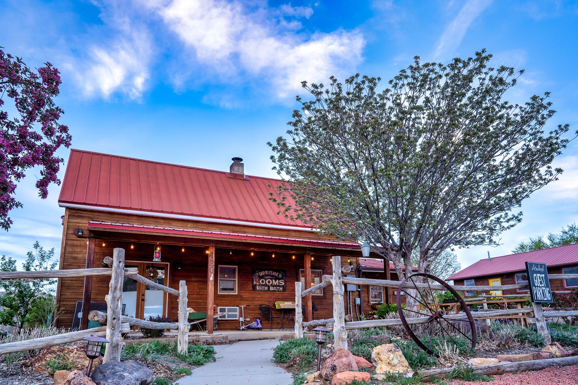 A log cabin with a red roof and a fence around it