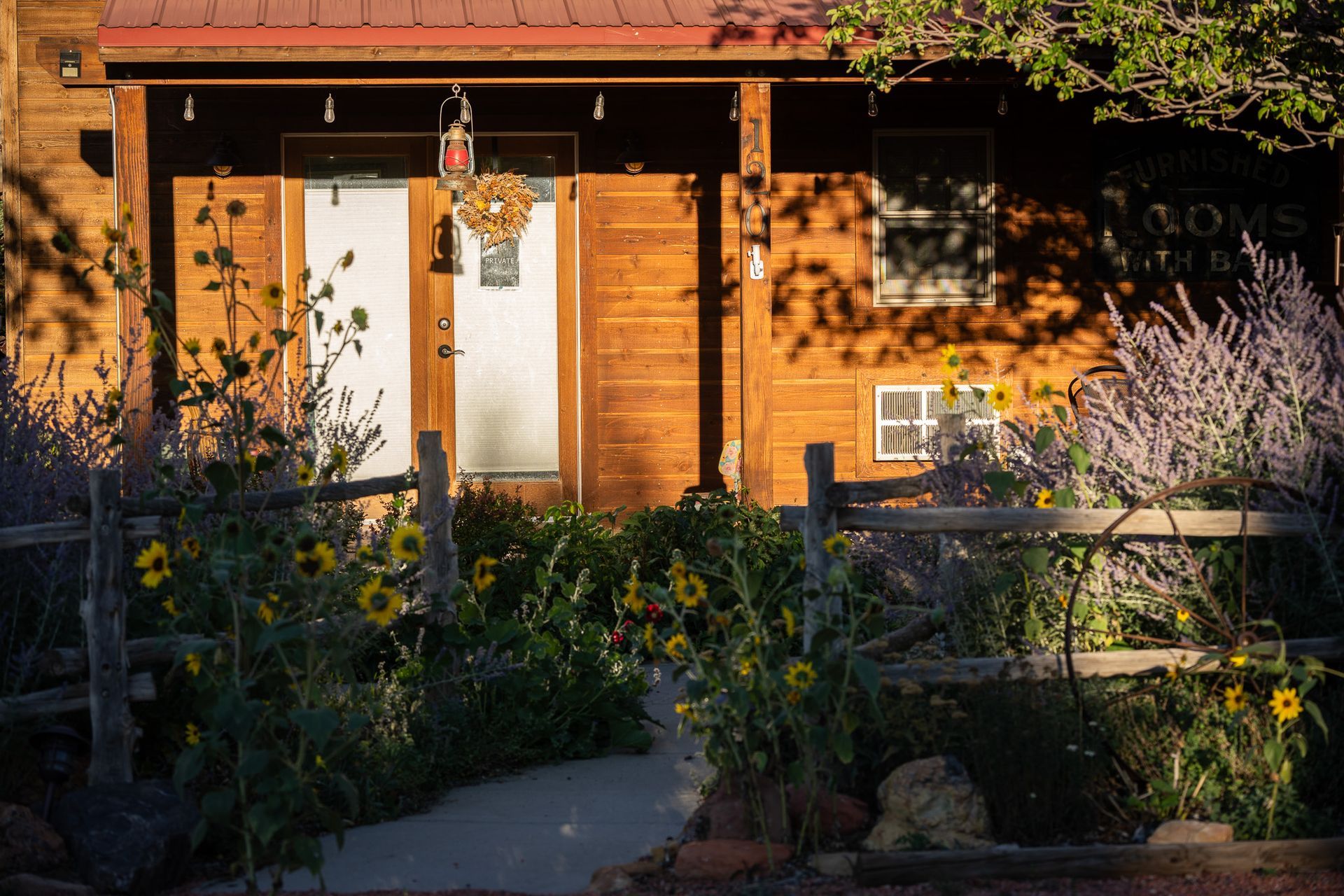A wooden house with a fence and flowers in front of it.