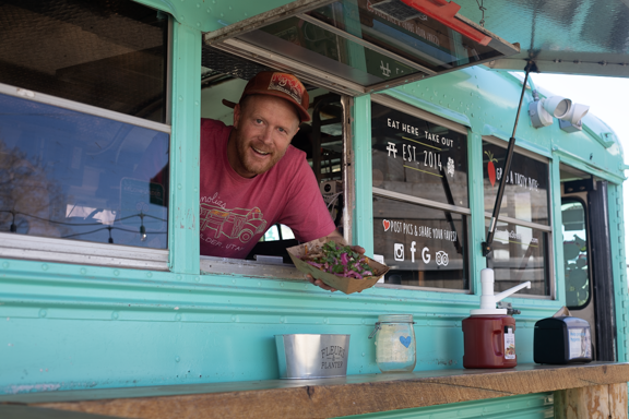 A pulled pork sandwich with coleslaw on a pink plate on a wooden table.