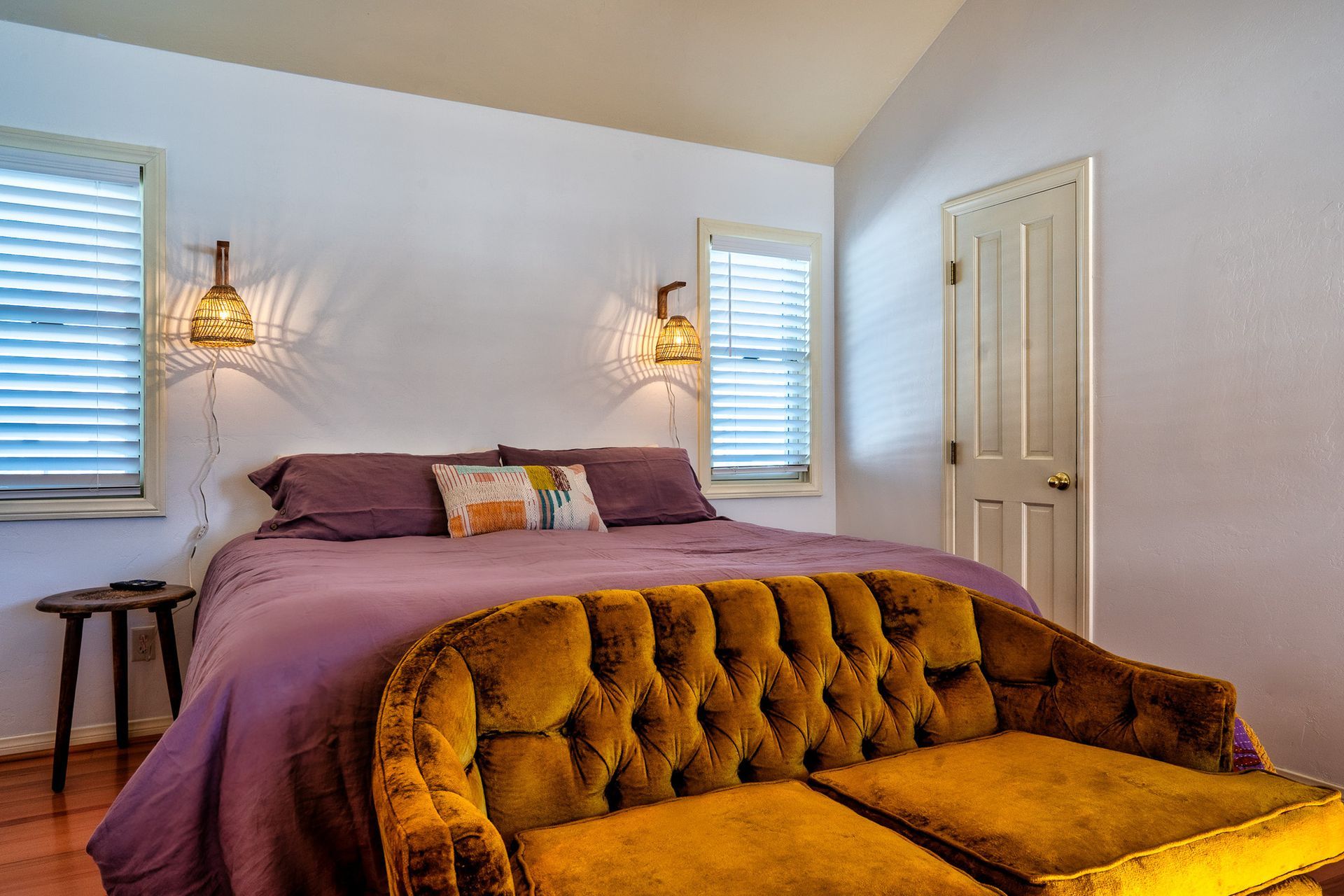 A bedroom with a bed , couch , and two windows.