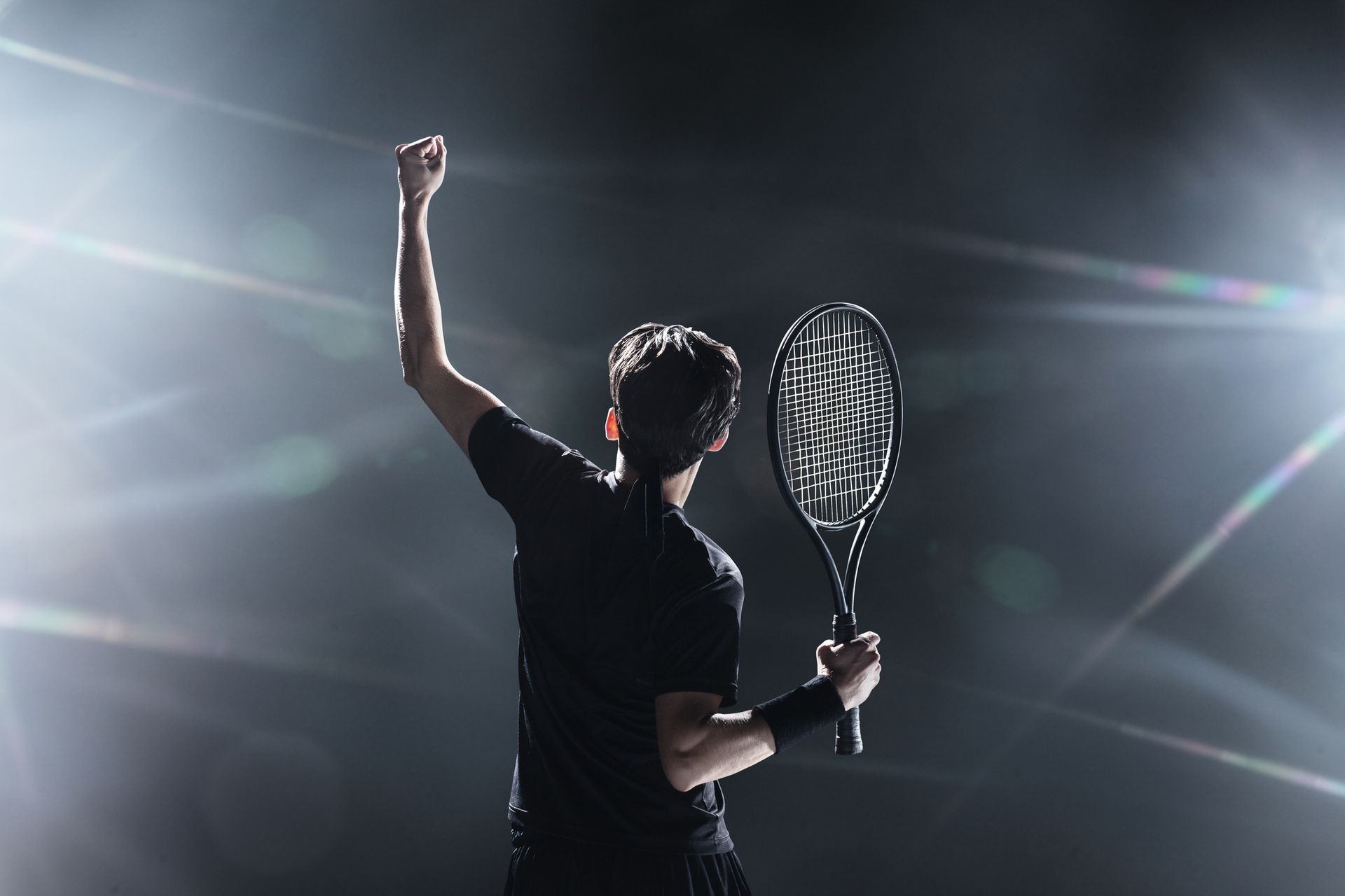 Un uomo tiene in mano una racchetta da tennis con il pugno alzato in aria.