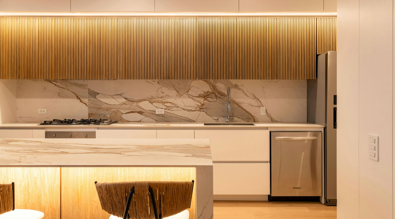 Modern kitchen with wooden upper cabinets, marble backsplash, island, and stainless steel appliances.