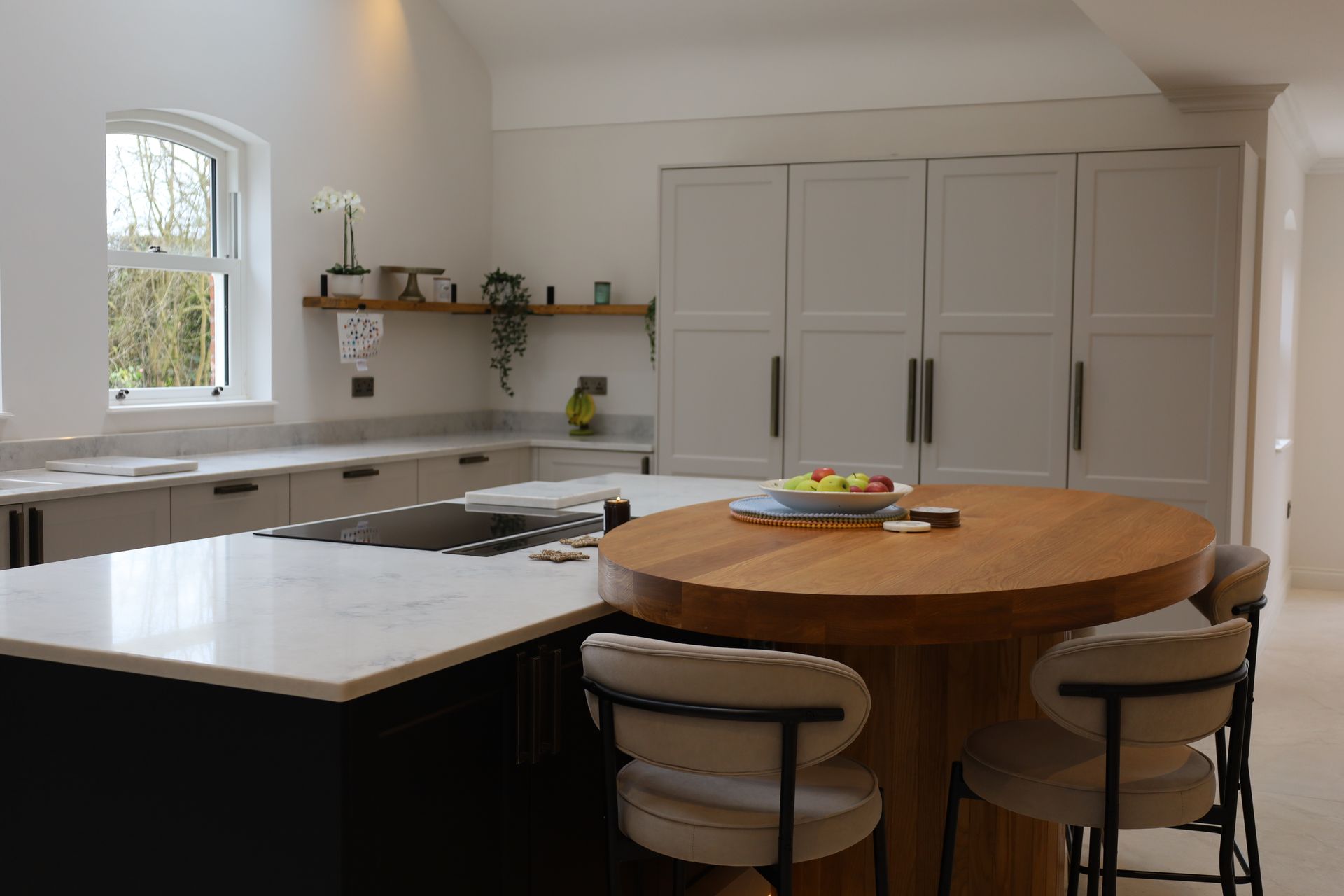 Luxury Kitchen Designed by James James Kitchens with wooden table, light cupboards and a marble island feature