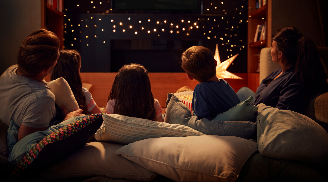 Family watching a Christmas Movie cosy with cushions and lights Family watching a Christmas movie
