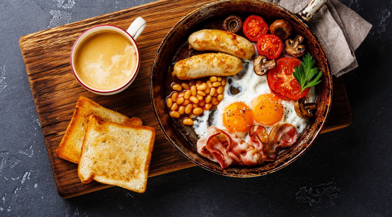 Festive full English breakfast idea displayed in a hot pan on a board Full English breakfast idea for Christmas on a wooden board and in a pan