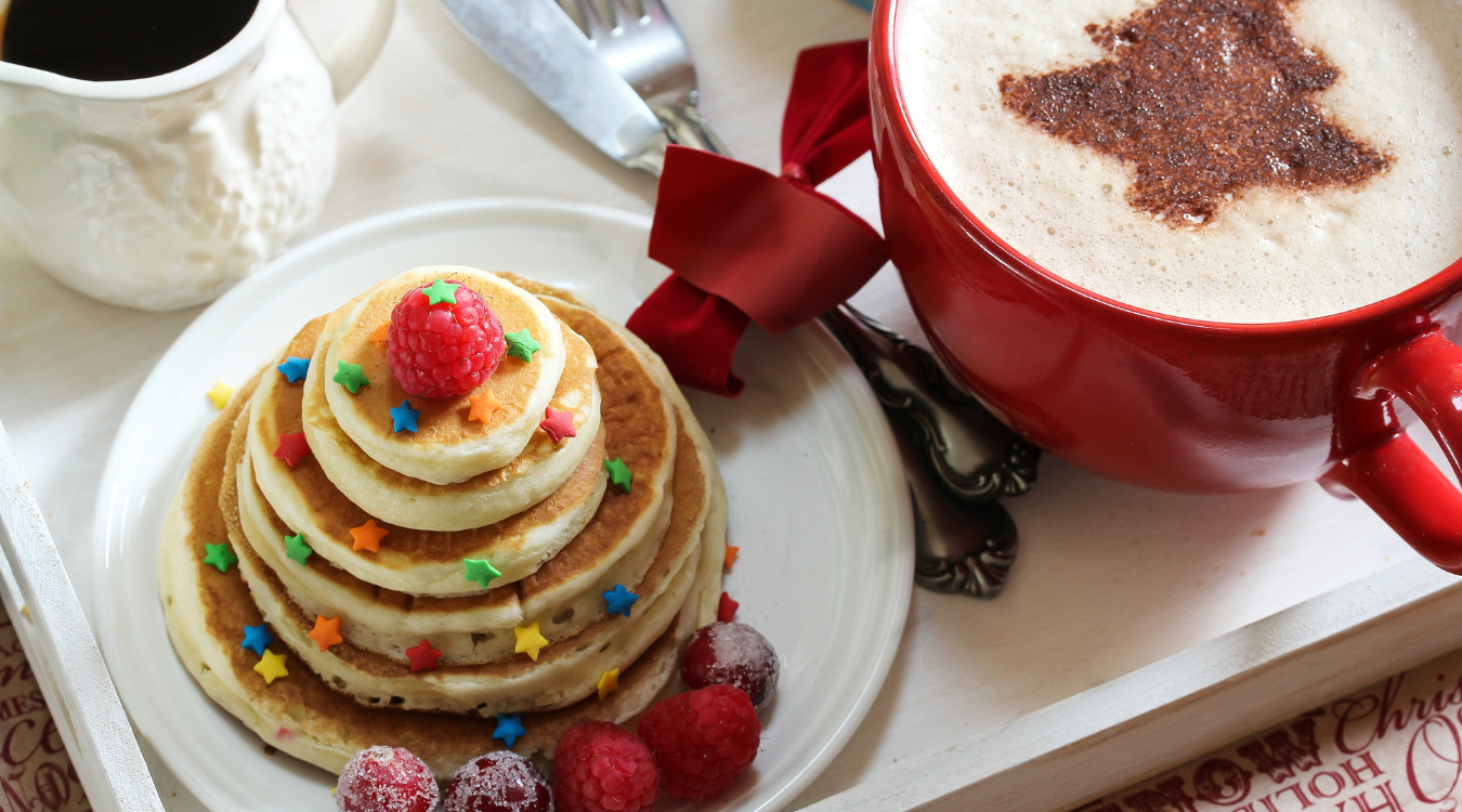 Christmas pancakes and a festive hot chocolate in a red mug Fluffy American pancakes decorate with Christmas stars next to a festive hot chocolate