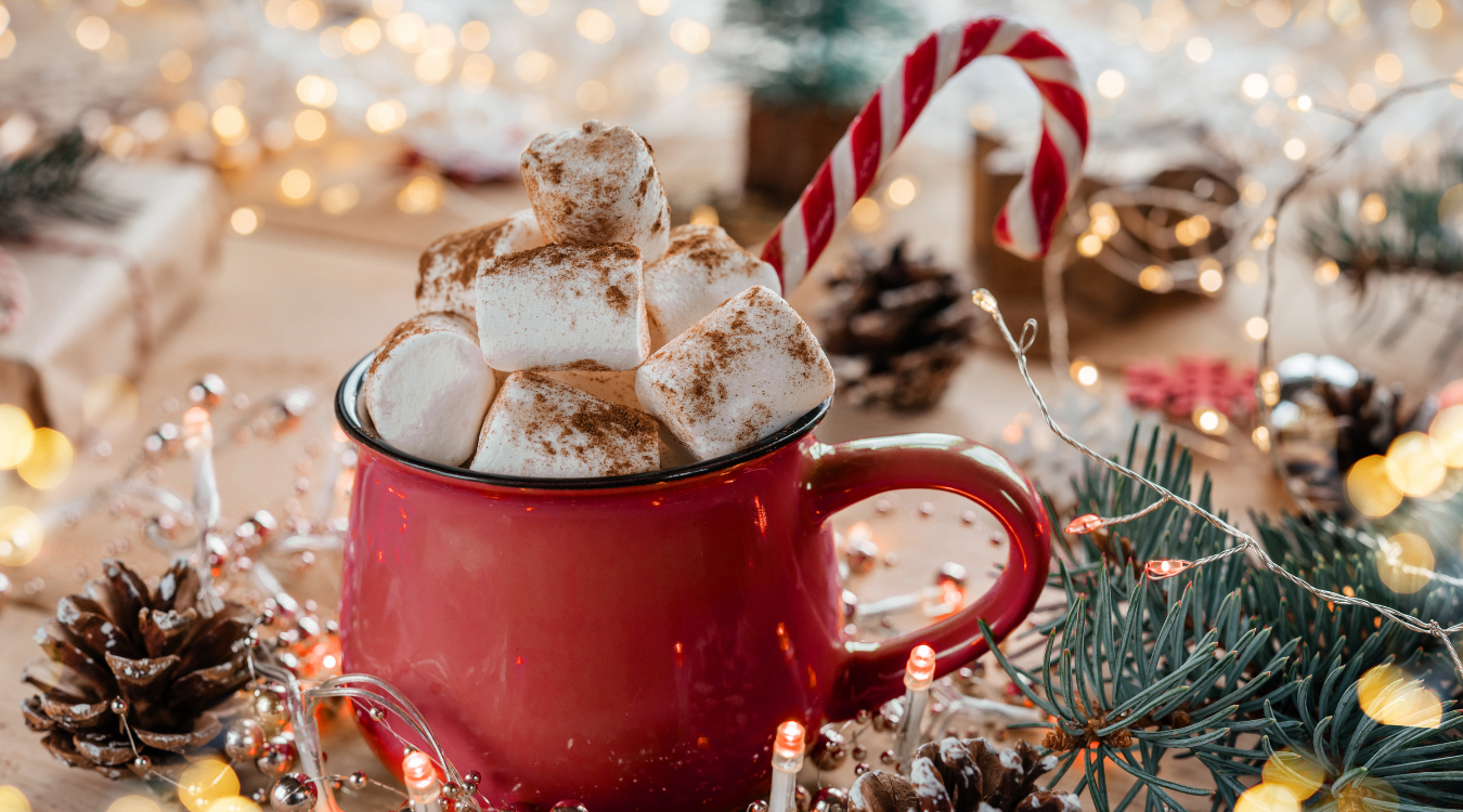 Festive hot chocolate in a red mug and surrounded by Christmas decorations