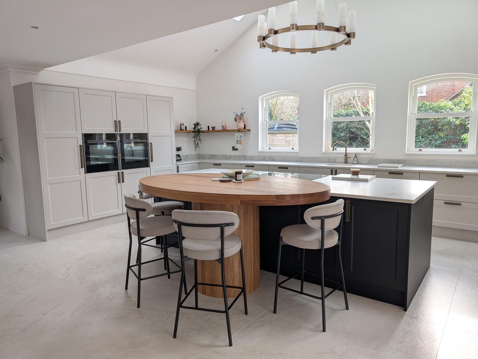 A bright luxury kitchen designed by James James Kitchens with a beautiful wooden island table
