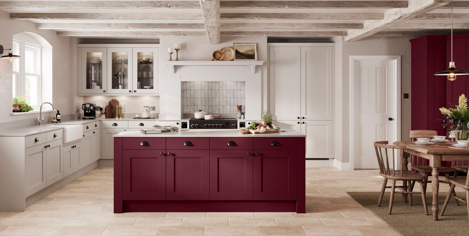 A kitchen with white cabinets and burgundy cabinets and a large island in the middle.