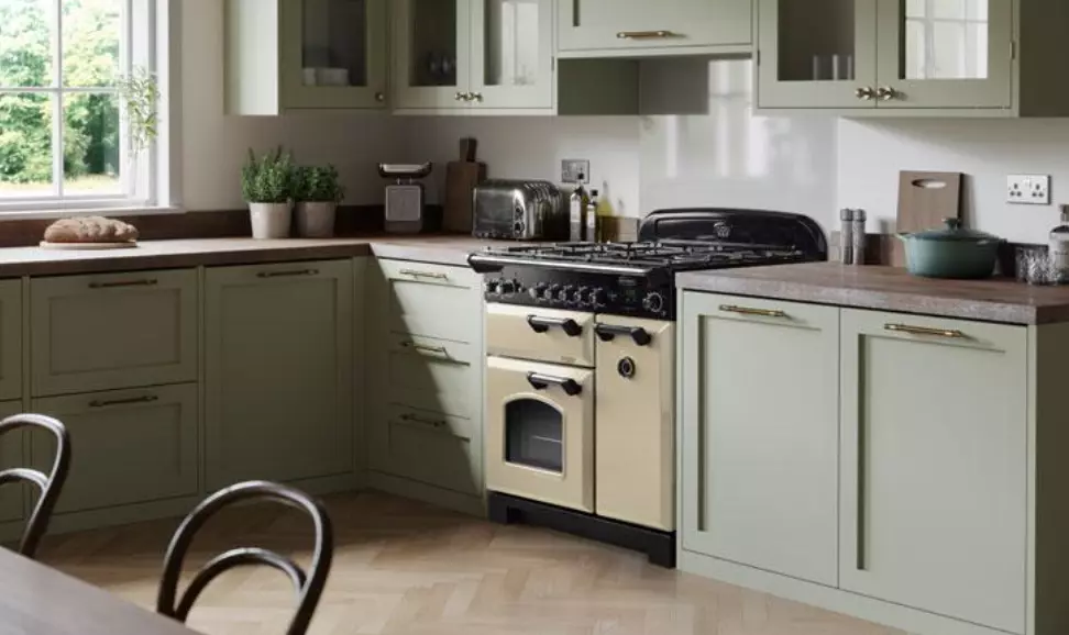 A kitchen with green cabinets , a stove , and a table.
