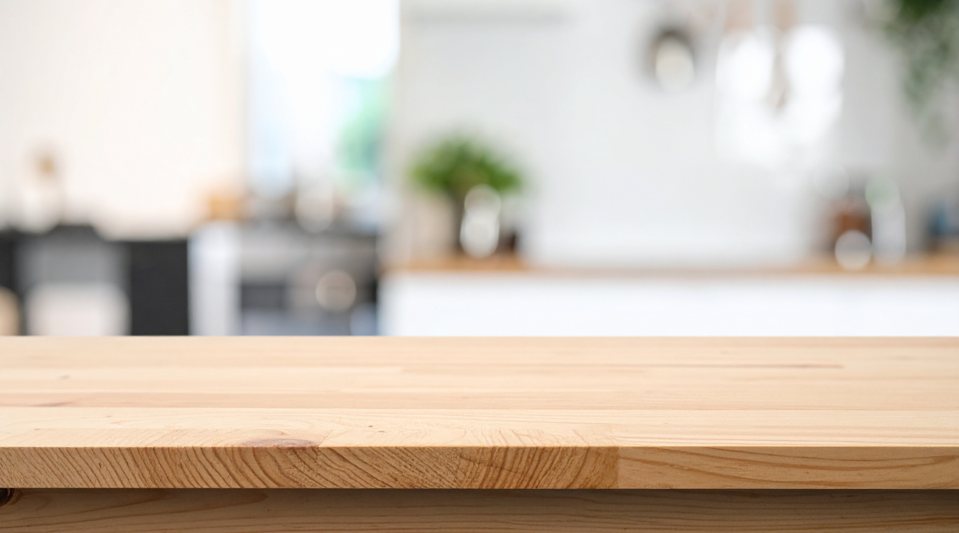 Wooden tabletop in focus, blurred modern kitchen in the background