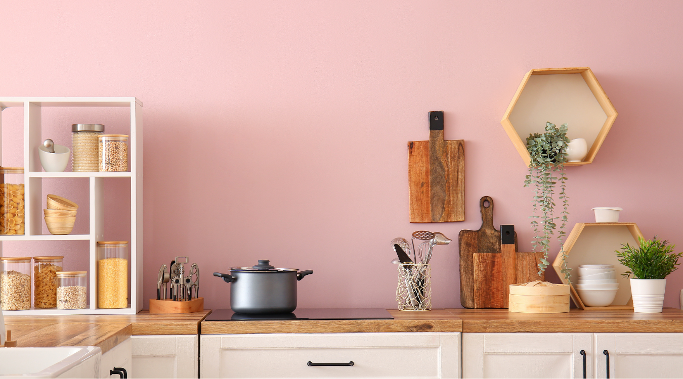 Pink kitchen with white cabinets, wooden countertops, and open shelving.