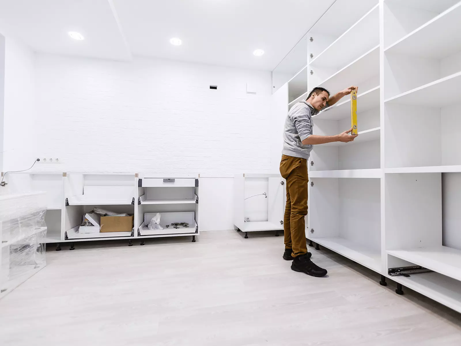 A man is measuring a shelf with a tape measure.