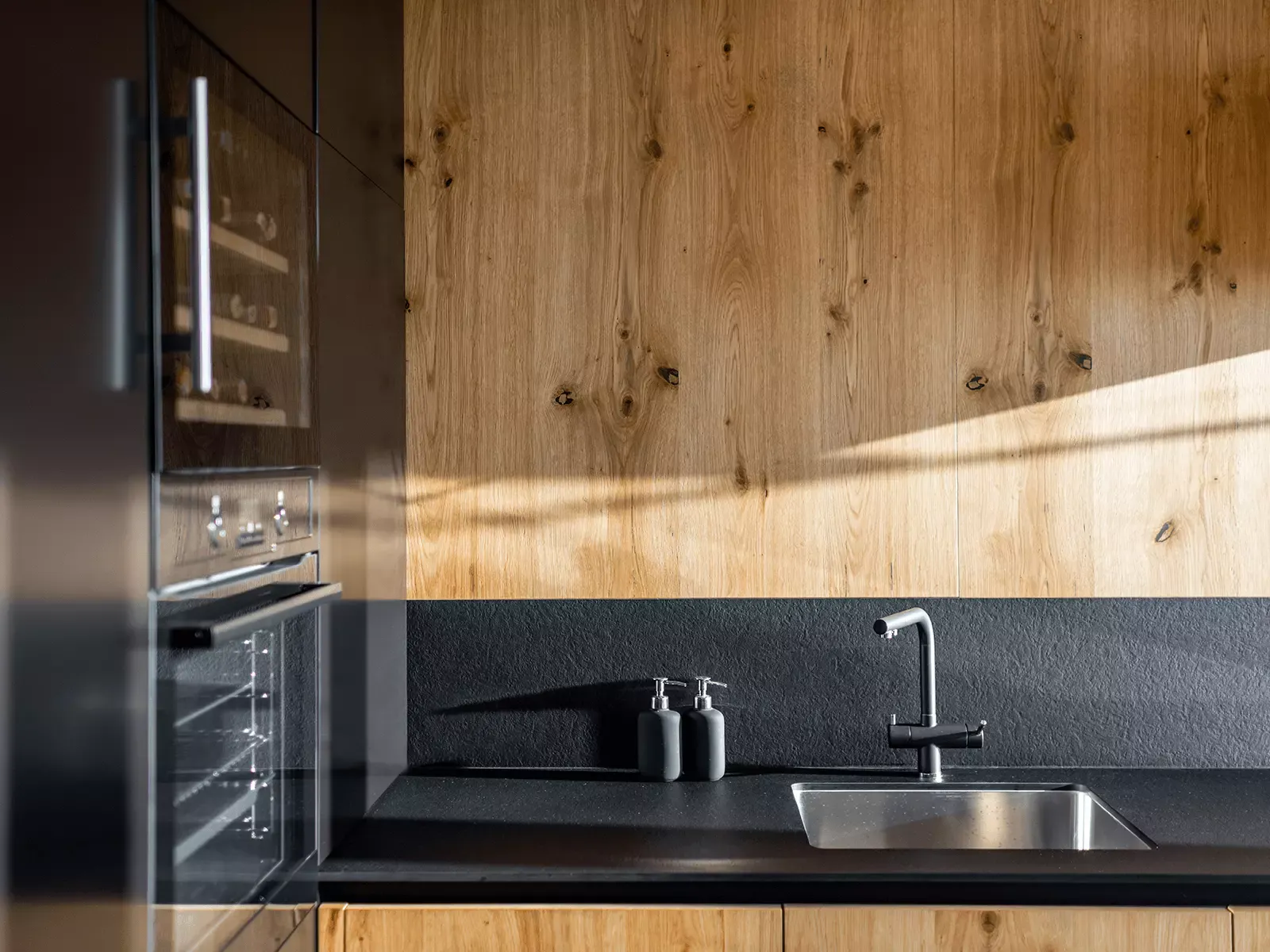 A kitchen with a sink , refrigerator , oven and wine cooler.