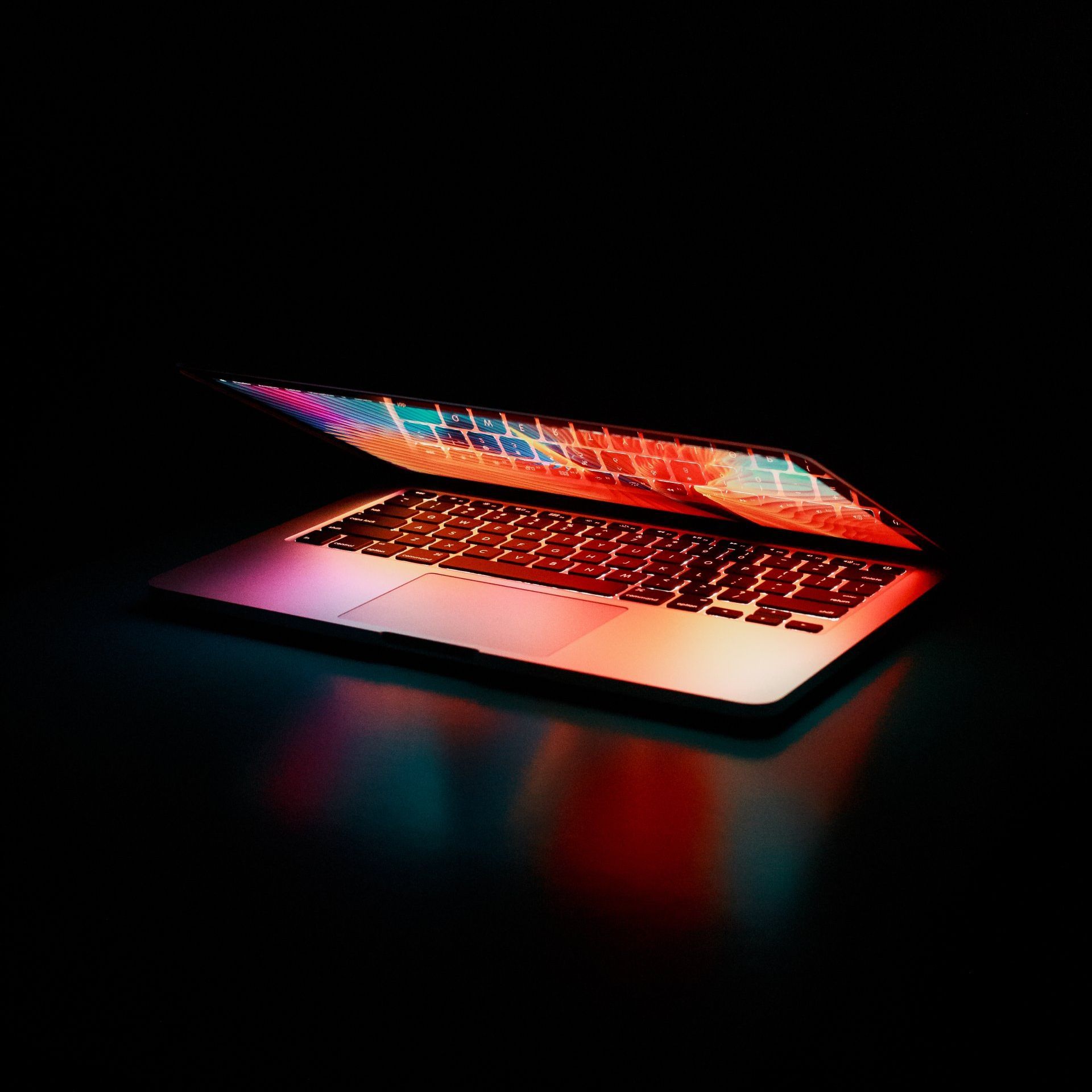 A laptop computer is open and sitting on a table in the dark.