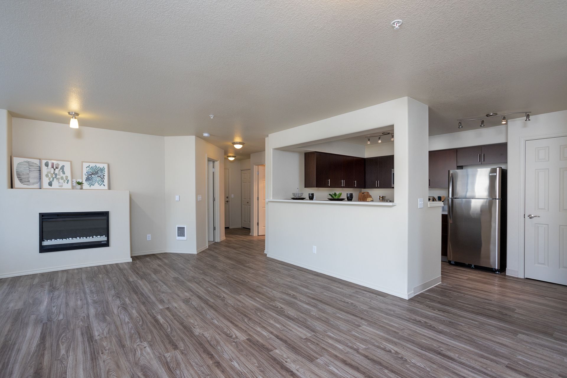 A living room with a fireplace and a stainless steel refrigerator