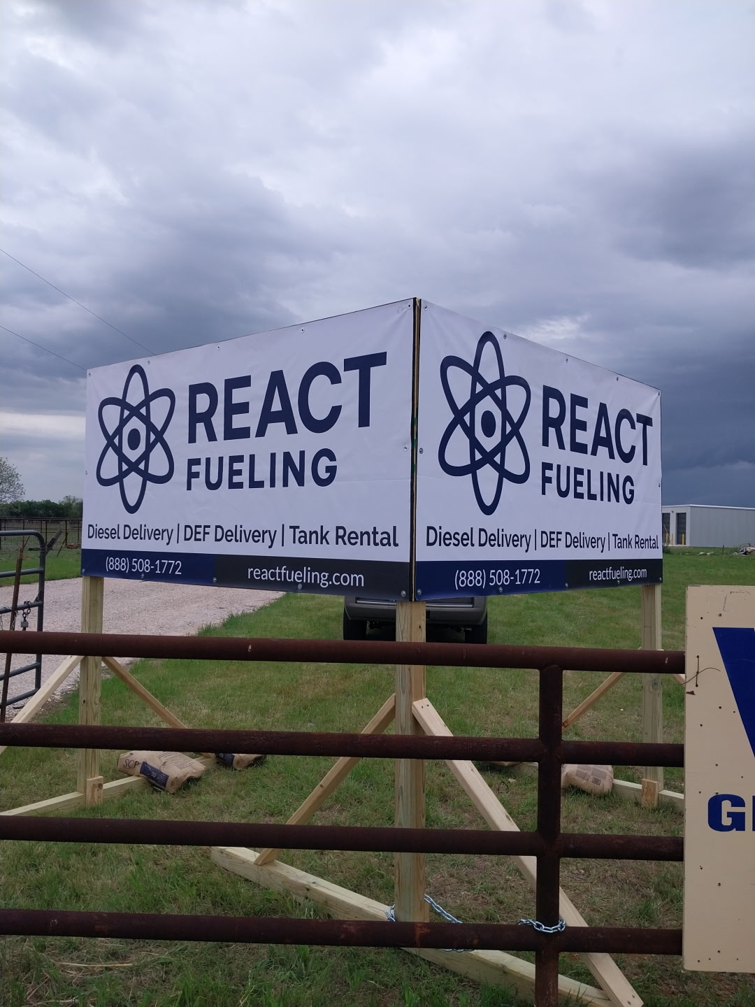 React Fueling sign on wooden gate under cloudy sky in a rural field