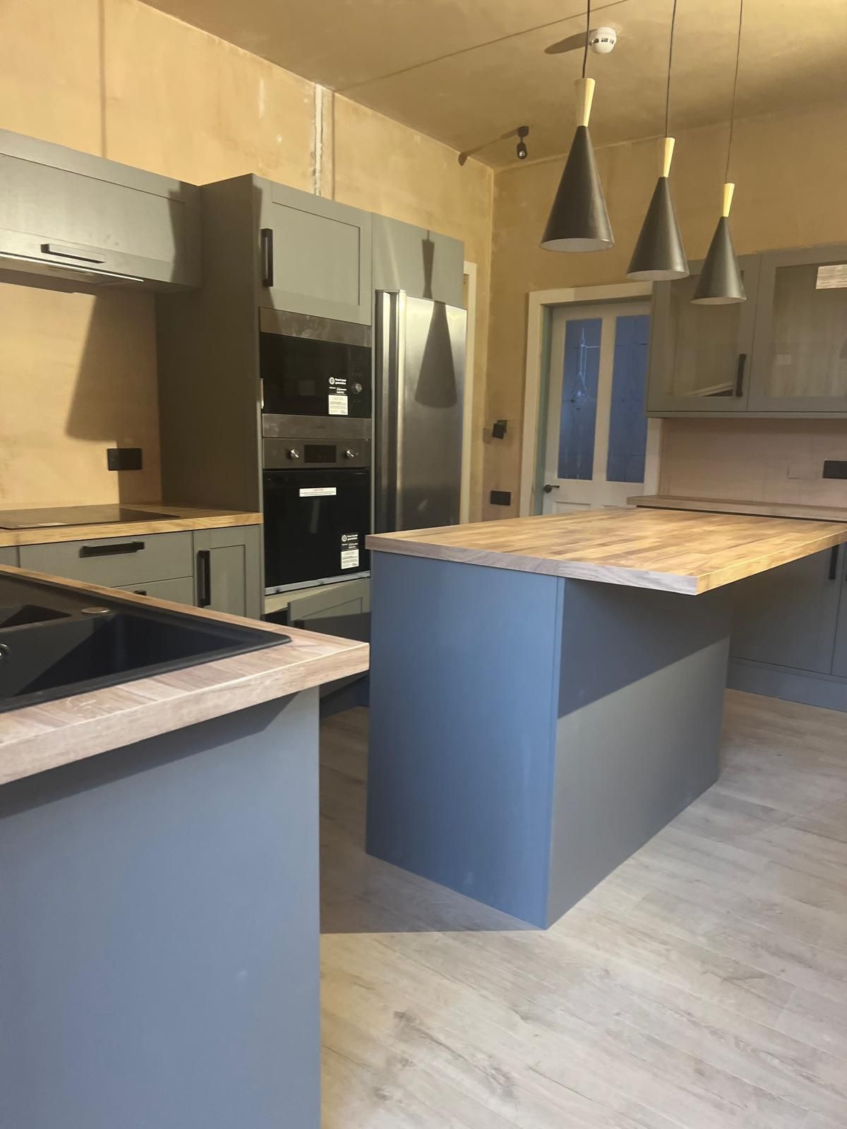 Gray kitchen with wood countertops and pendant lights.