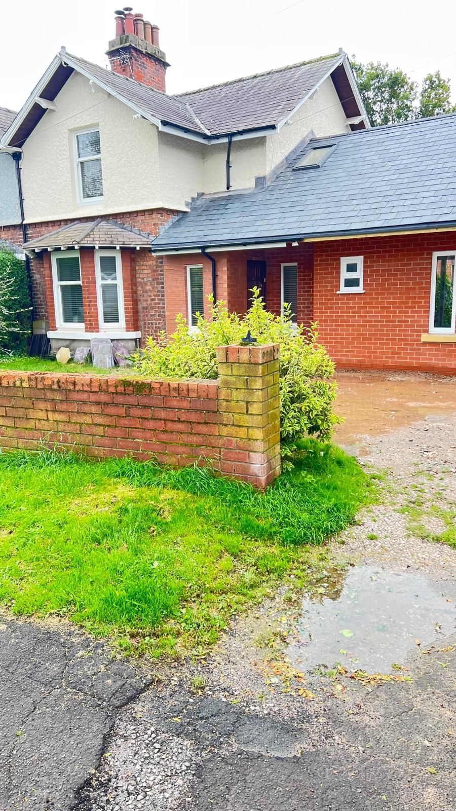 Red brick house with a low brick wall and a patch of grass.