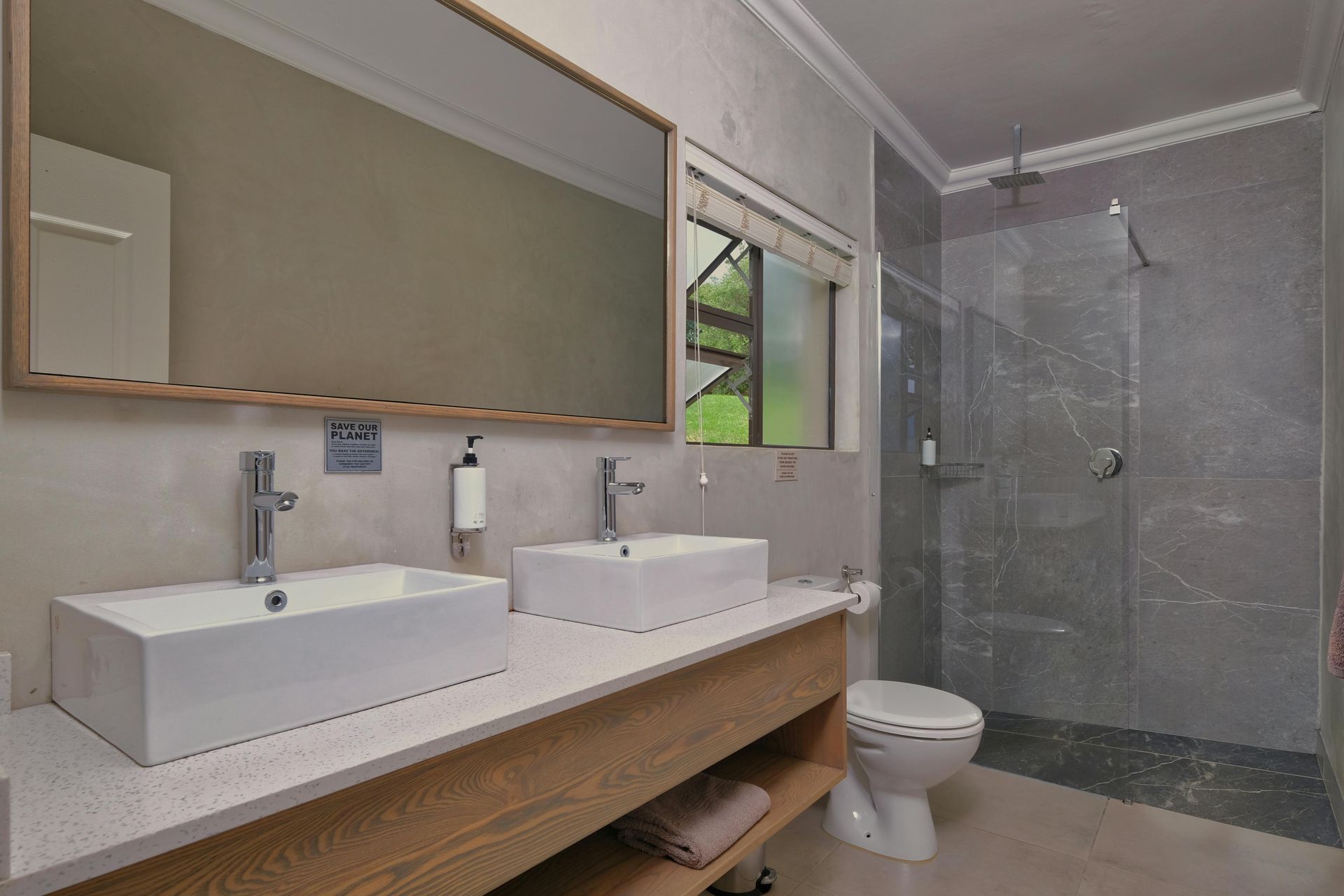 Modern bathroom with two sinks, a toilet, and a glass shower.