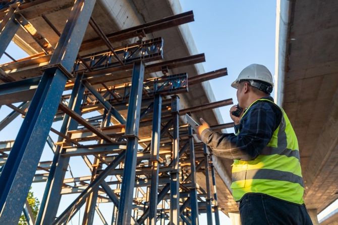 Construction worker inspecting steel structural beams on a job site.