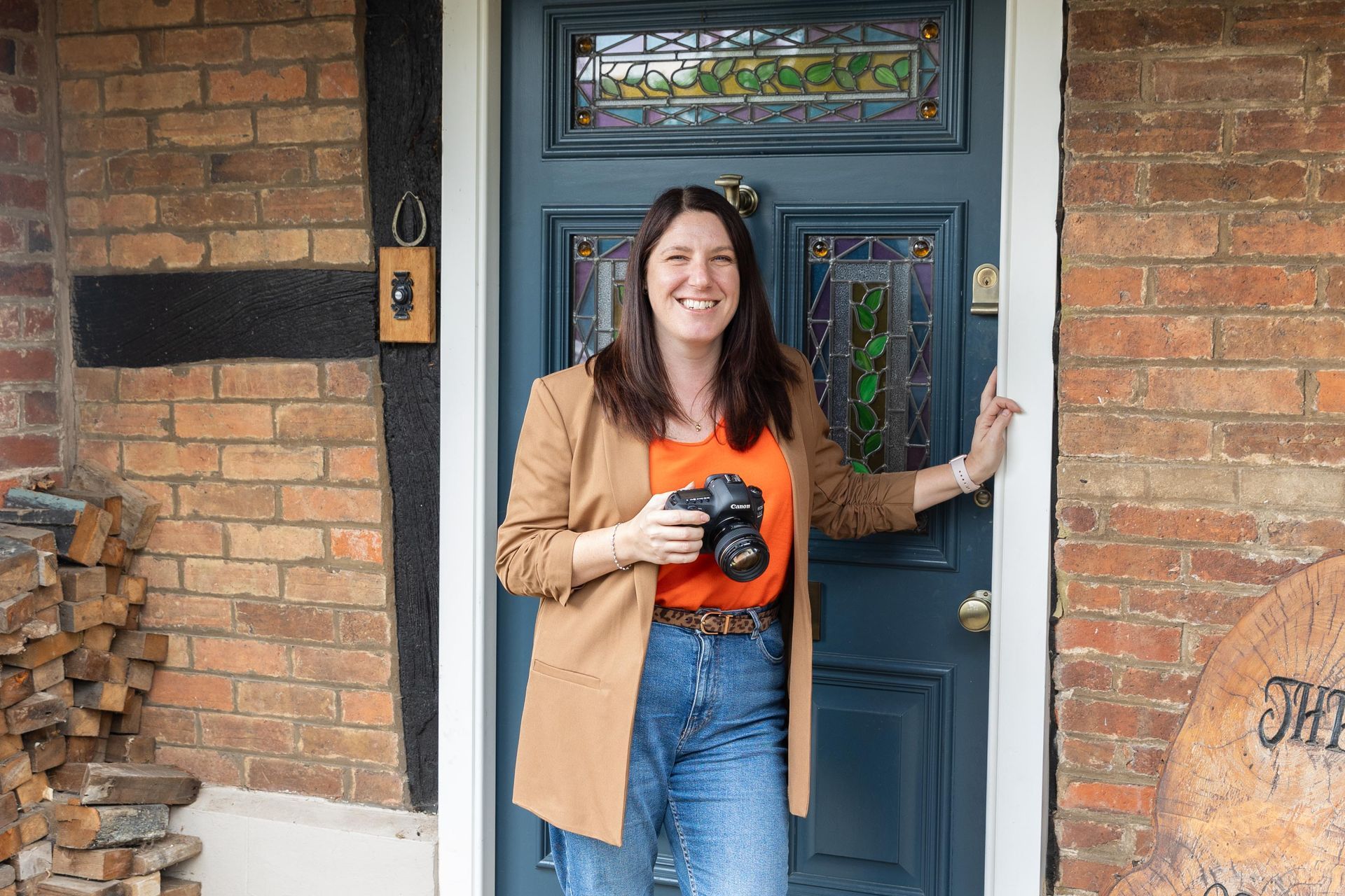 Woman standing at a doorway holding a camera