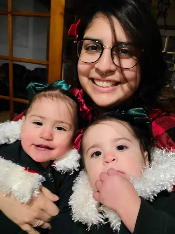A woman is holding two little girls in her arms.