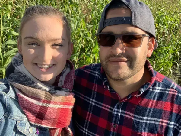 A man and a woman are posing for a picture in a corn field.