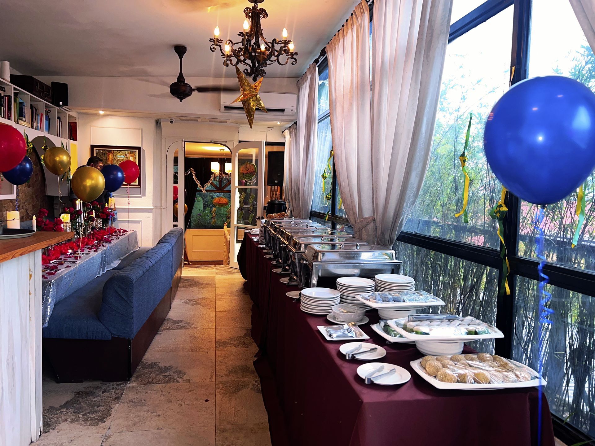 Buffet setup at an event, featuring food, a blue sofa, and balloons.
