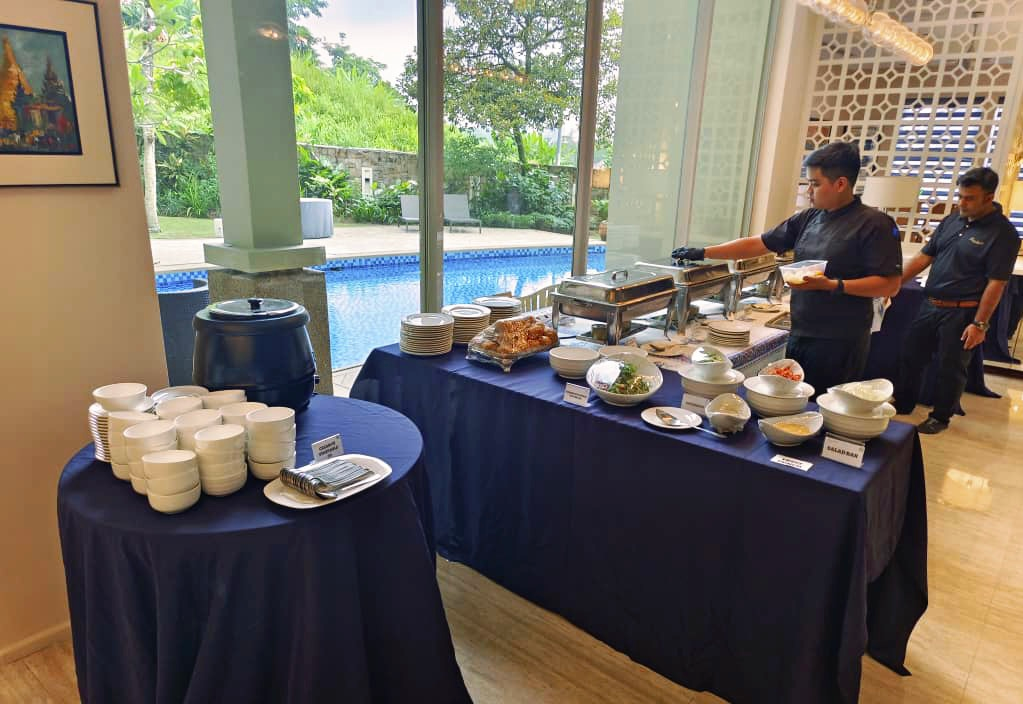 Catered buffet setup with staff; a pool visible behind the tables.