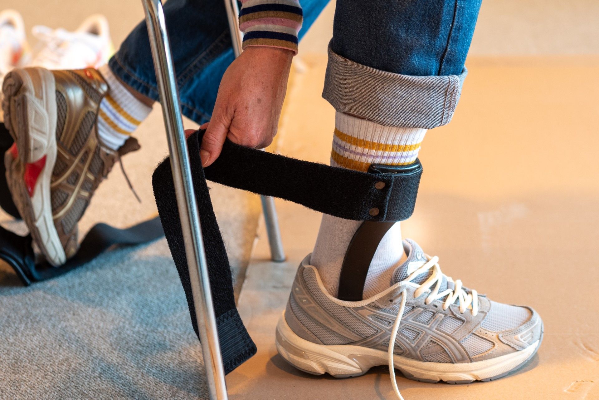 To ortopædiske ankel-fodortoser (AFO'er) med en sko, sort og hvid, mod en hvid baggrund.