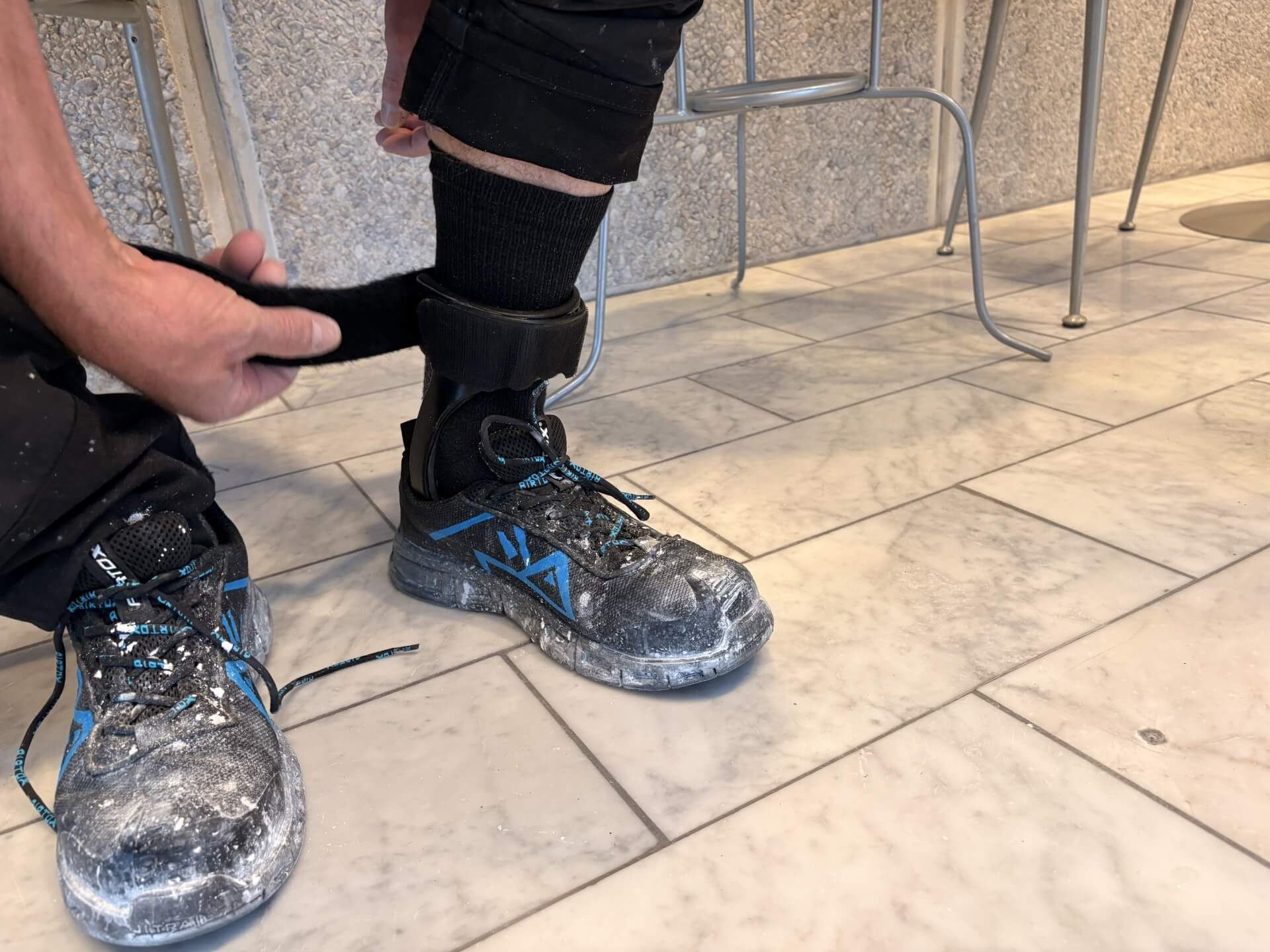 En person iført sikkerhedsudstyr betjener et slibeværktøj i et værksted.